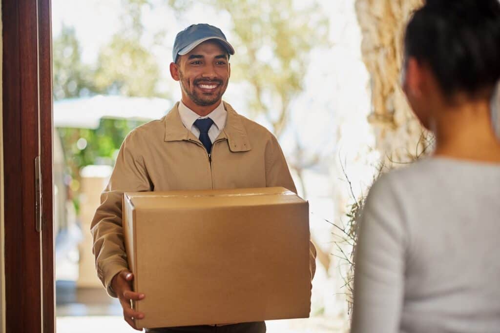 Smiling delivery person delivering a package to a customer at her home