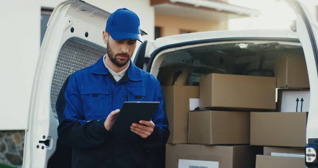 Delivery man in blue uniform checking information on a hand-held tablet