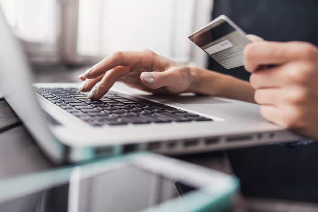 Person using a laptop holding a credit card to complete an e-commerce transaction, illustration of e-commerce driving autonomous last-mile market growth 