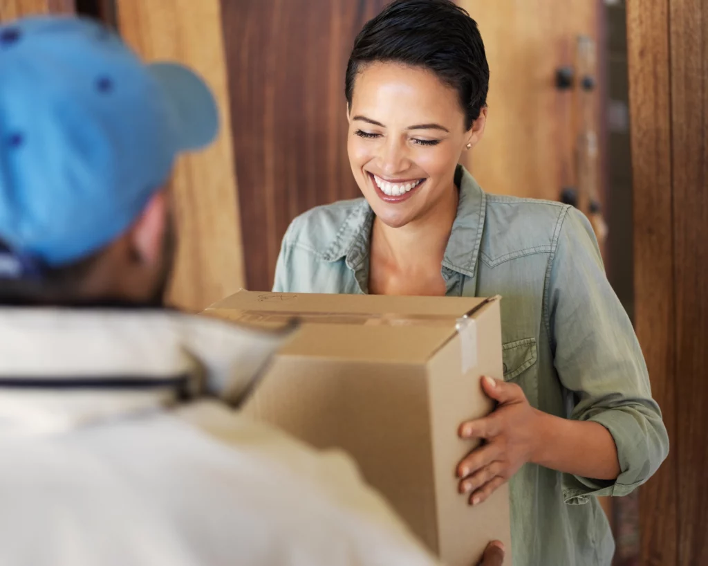 Smiling woman receiving a package from a delivery driver